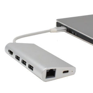 A silver USB C hub with multiple ports including HDMI, Ethernet, SD/TF card reader, and USB Type-C, connected to a laptop.
