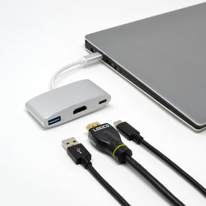 A silver USB Type C hub connected to a laptop, with HDMI and USB cables alongside.