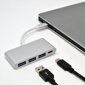 A silver 4 in 1 USB C hub with three USB 3.0 ports and one USB Type C port, connected to a laptop.